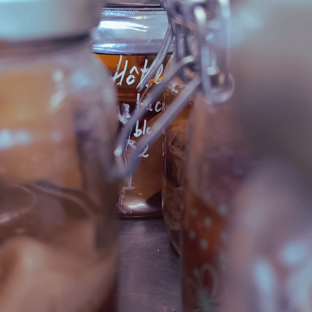 Des jargons avec du kombucha brun à l'intérieur, montrant la fermentation en cours